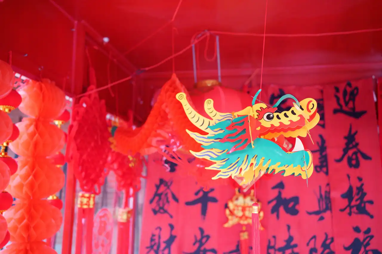 Une décoration traditionnelle de Nouvel An chinois avec une grande tête de dragon colorée suspendue sur fond de lanternes et de banderoles rouges.