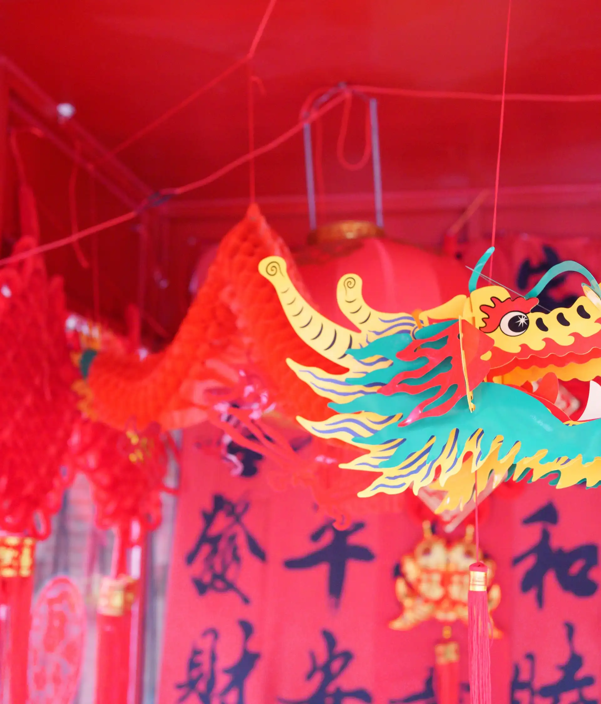 Une décoration traditionnelle de Nouvel An chinois avec une grande tête de dragon colorée suspendue sur fond de lanternes et de banderoles rouges.