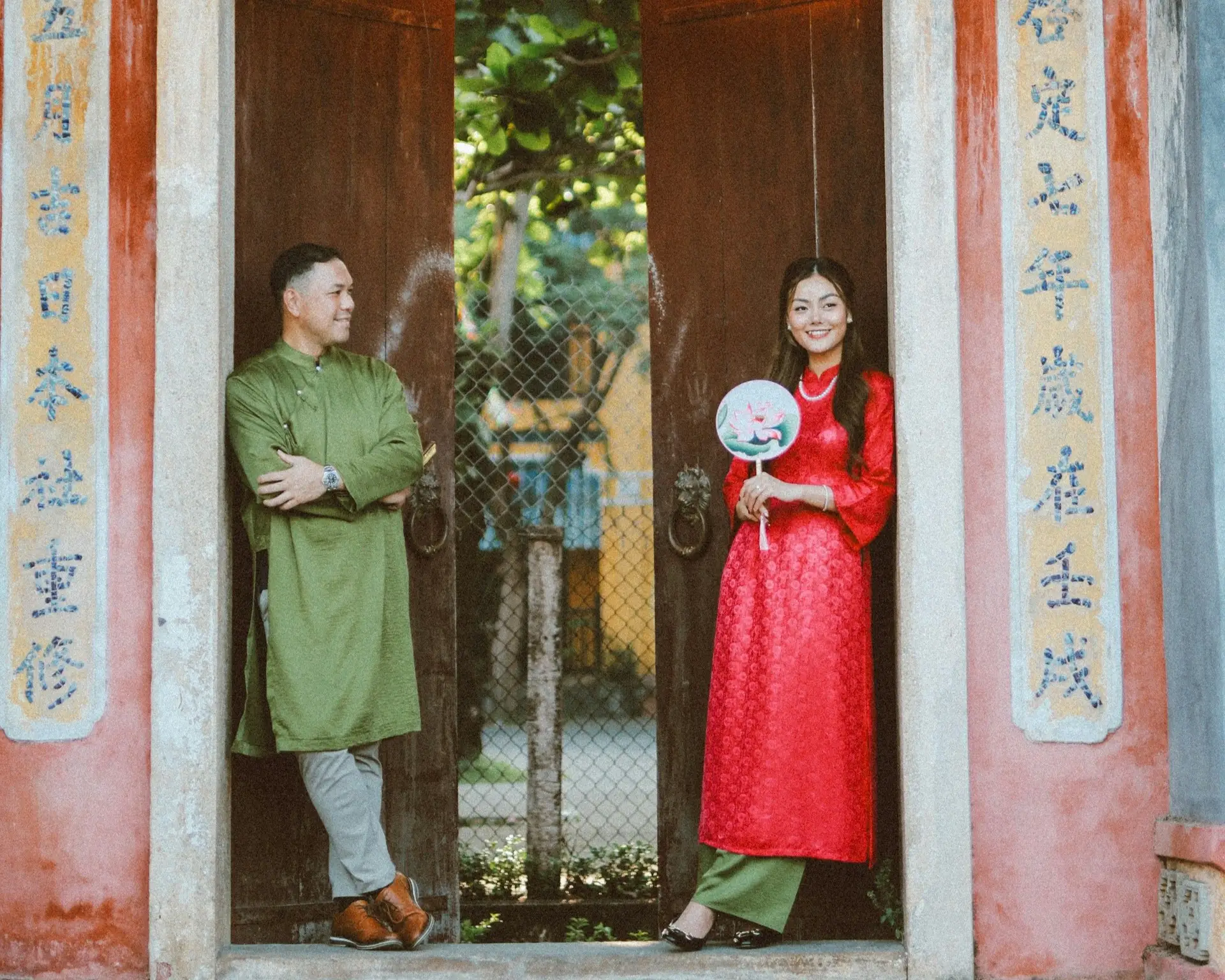 Un couple en tenues élégantes posant devant une porte traditionnelle chinoise en bois, illustrant le style vestimentaire idéal pour un voyage réussi en Chine.