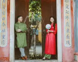 Un couple en tenues élégantes posant devant une porte traditionnelle chinoise en bois, illustrant le style vestimentaire idéal pour un voyage réussi en Chine.