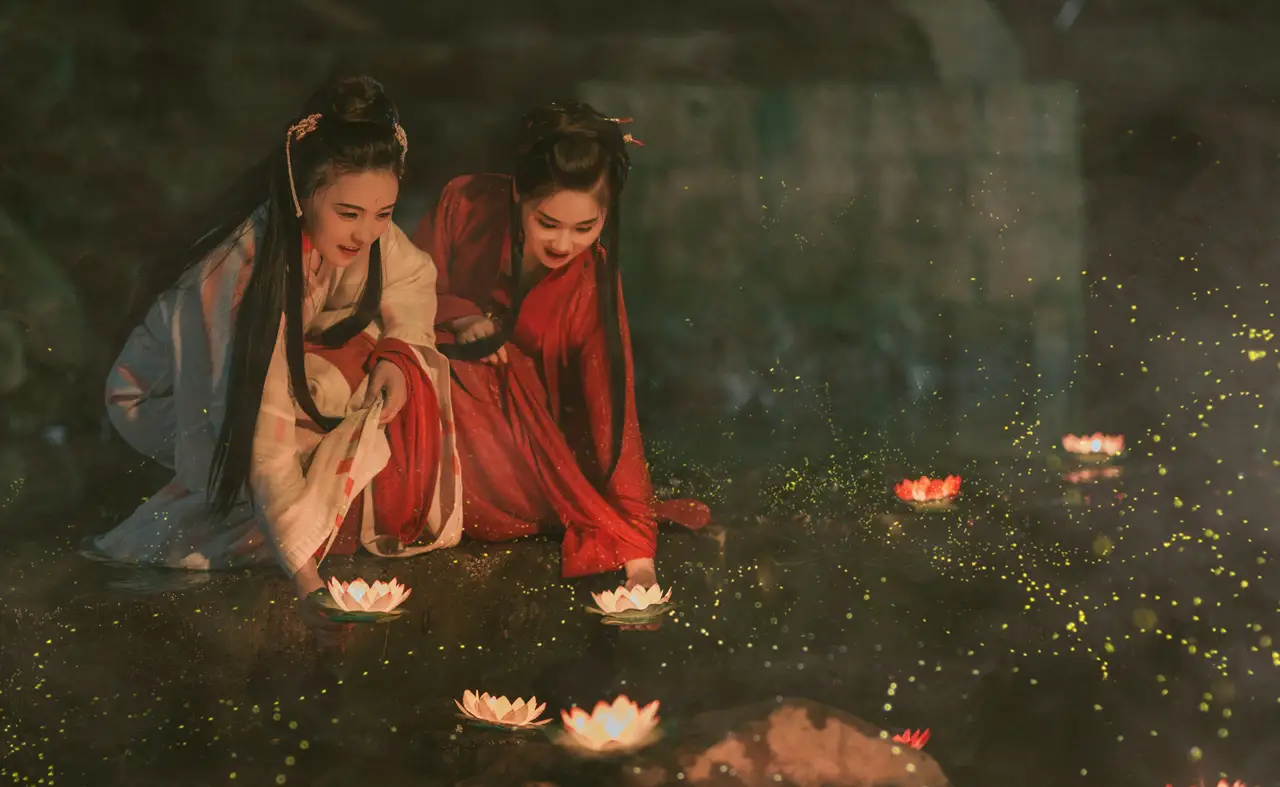 Voyage en Chine – Deux femmes portant des vêtements traditionnels Hanfu au bord de l'eau avec des lanternes, illustrant l'héritage culturel chinois.