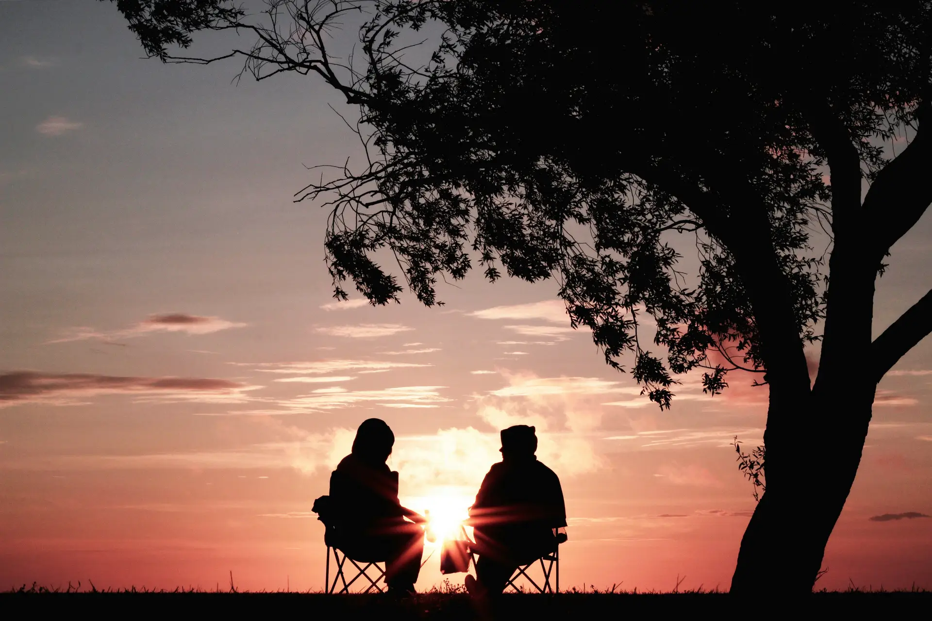 Travel in Asia - A couple sitting under a tree watching the sun set over the horizon