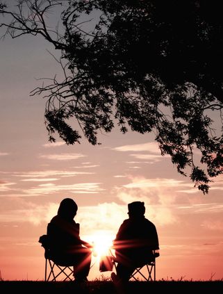 Travel in Asia - A couple sitting under a tree watching the sun set over the horizon