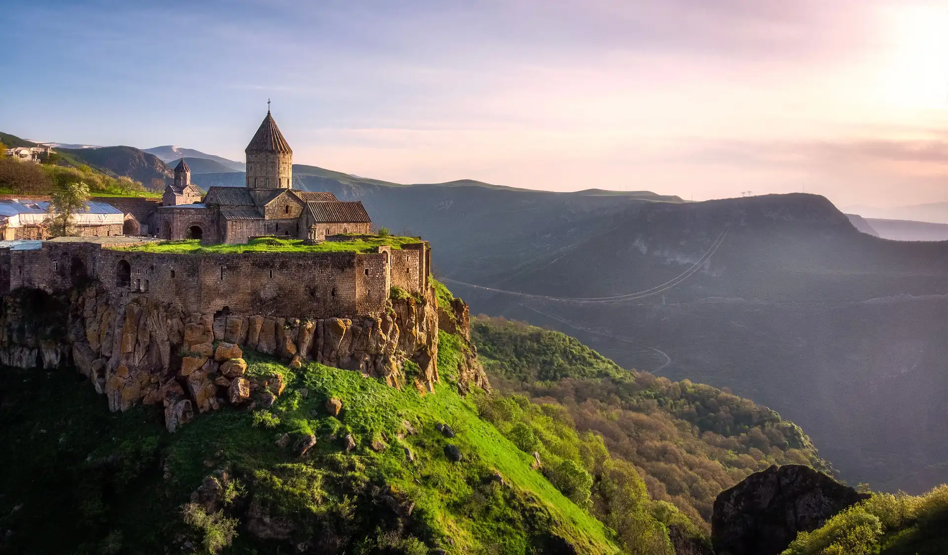 Voyage en Arménie : vue sur le monastère de Tatev entouré de montagnes verdoyantes.