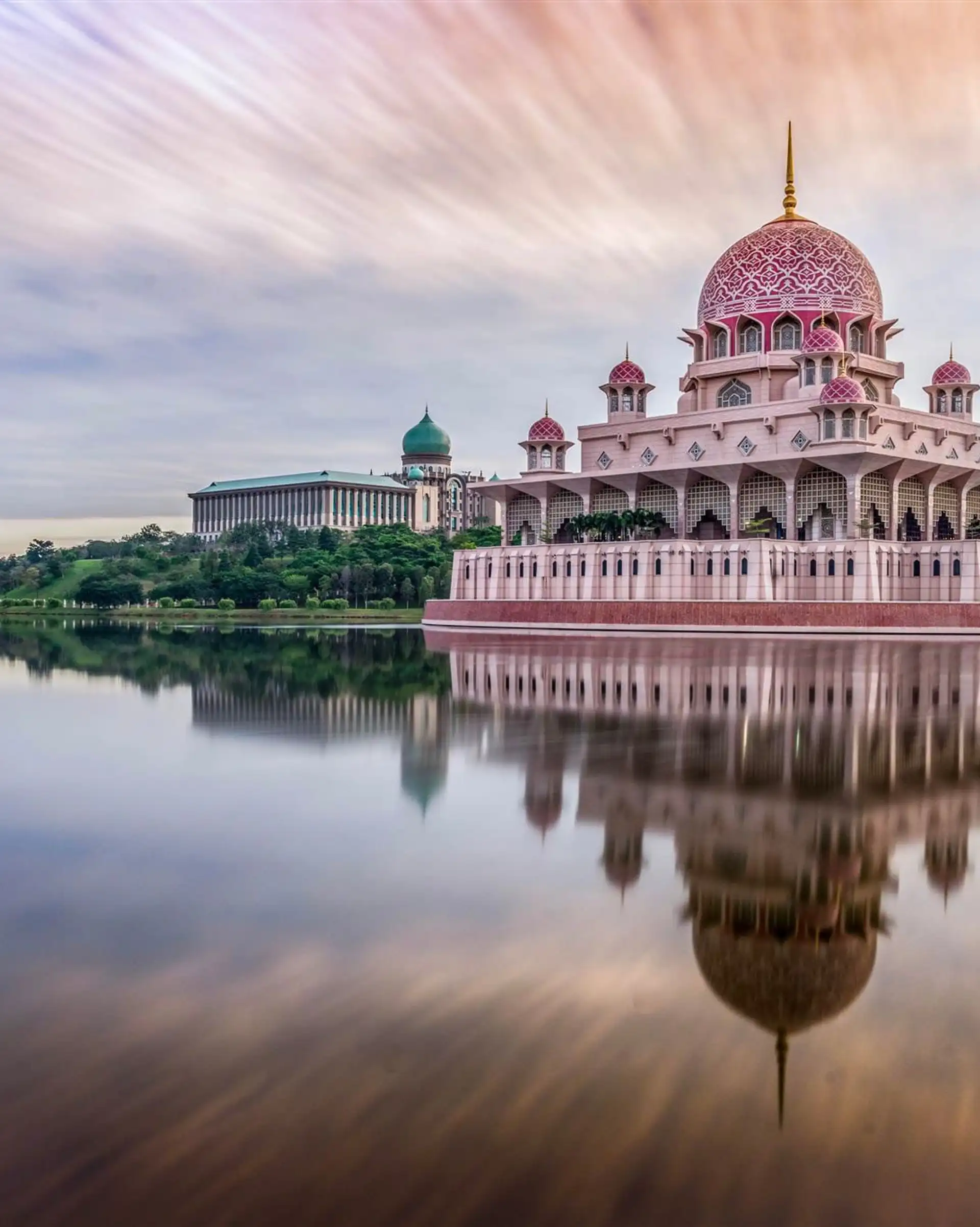 La majestueuse mosquée rose Putra se reflétant dans les eaux du lac à Putrajaya au coucher du soleil.