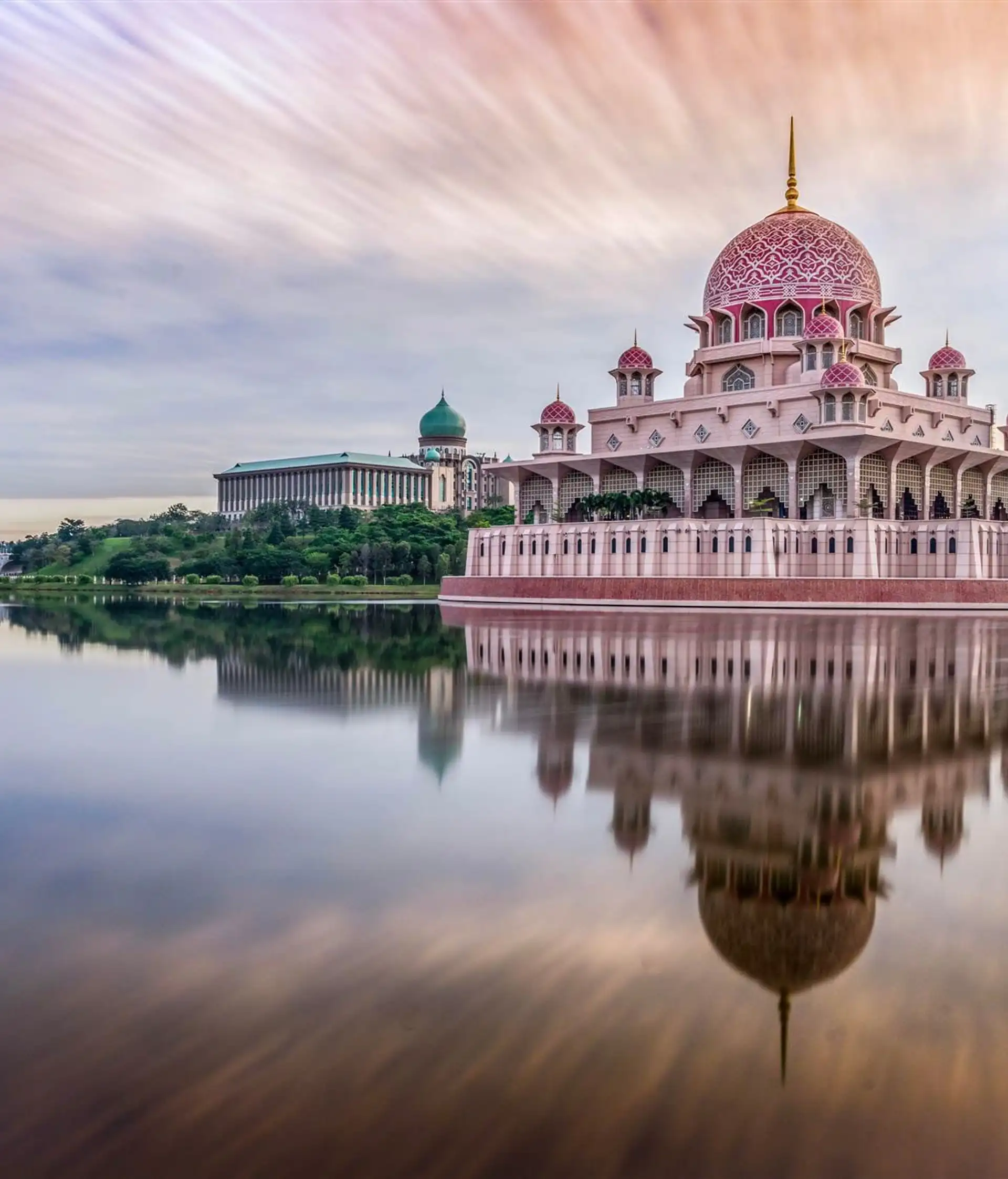 La majestueuse mosquée rose Putra se reflétant dans les eaux du lac à Putrajaya au coucher du soleil.