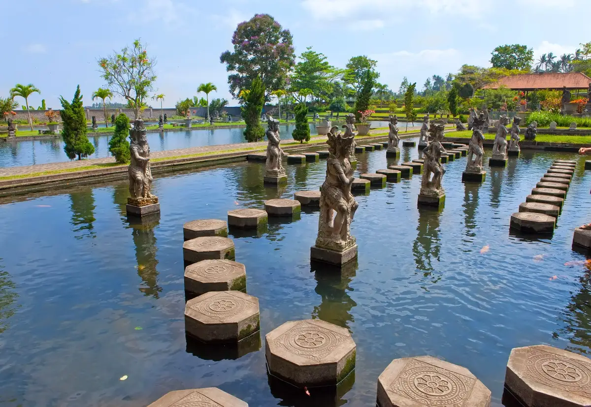 Les bassins sacrés du palais aquatique de Tirta Gangga, parsemés de dalles en pierre pour marcher sur l'eau et de statues sculptées traditionnelles à Bali.