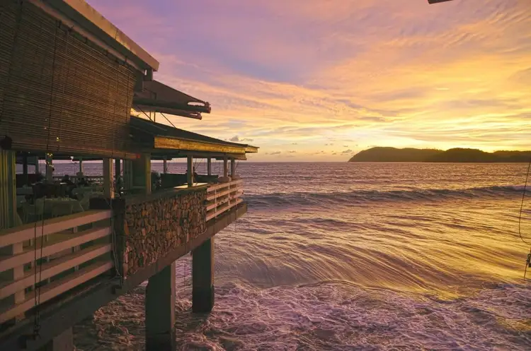 Vue d'un coucher de soleil spectaculaire depuis une terrasse en bord de mer à Langkawi, propice à la détente et aux célébrations.