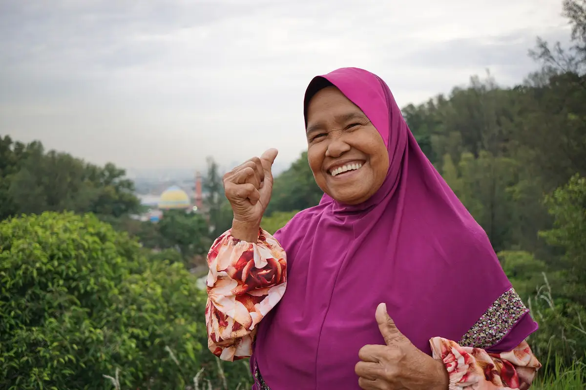 Portrait souriant d'une femme locale en tenue traditionnelle, symbole de l'accueil chaleureux rencontré en Malaisie.