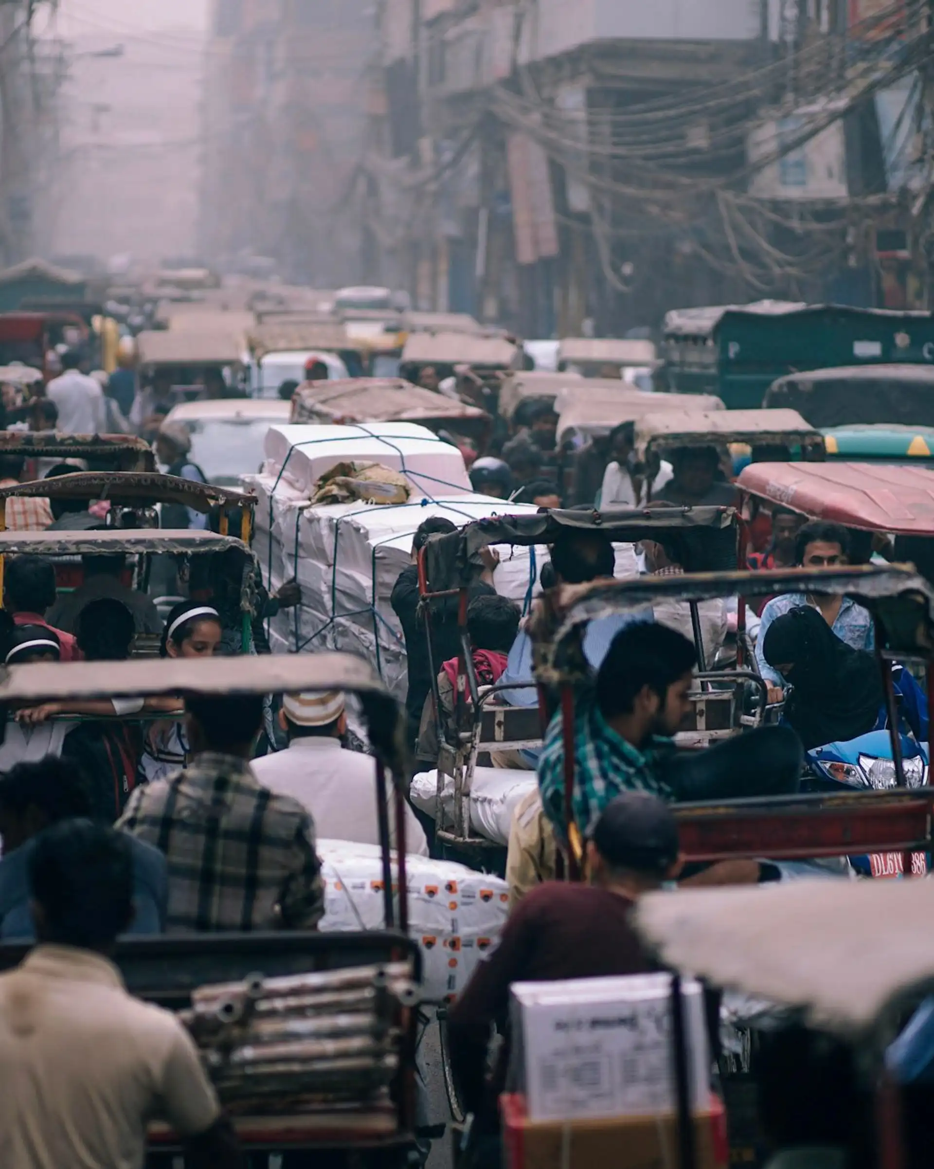 Voyage en Asie — Embouteillage urbain à Delhi avec une rue étroite remplie de rickshaws, de câbles électriques suspendus et de passagers immobiles dans la circulation.