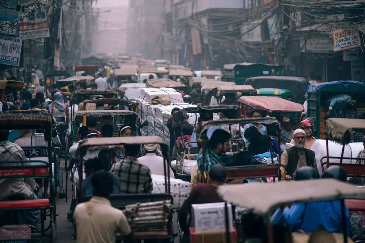 Voyage en Asie — Embouteillage urbain à Delhi avec une rue étroite remplie de rickshaws, de câbles électriques suspendus et de passagers immobiles dans la circulation.