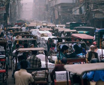 Voyage en Asie — Embouteillage urbain à Delhi avec une rue étroite remplie de rickshaws, de câbles électriques suspendus et de passagers immobiles dans la circulation.