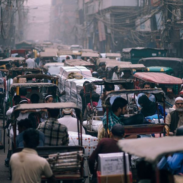 Voyage en Asie — Embouteillage urbain à Delhi avec une rue étroite remplie de rickshaws, de câbles électriques suspendus et de passagers immobiles dans la circulation.