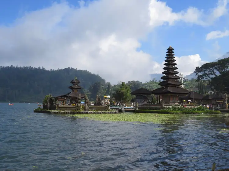 Les sanctuaires de style méru aux toits de chaume superposés du temple hindouiste d'Ulun Danu Bratan, se reflétant sur les eaux calmes du lac sous un ciel montagneux à Bali.