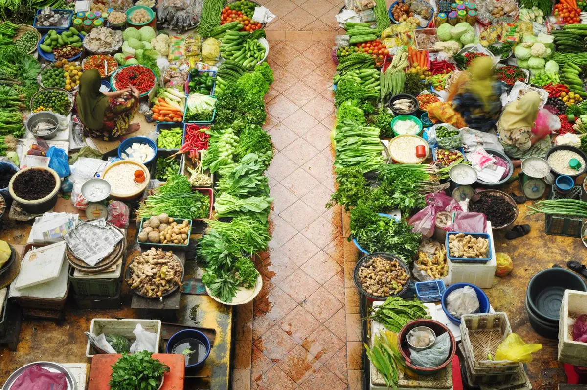 Vue plongeante sur les étals colorés d'un marché local à Ipoh, proposant une variété de produits frais et d'épices.