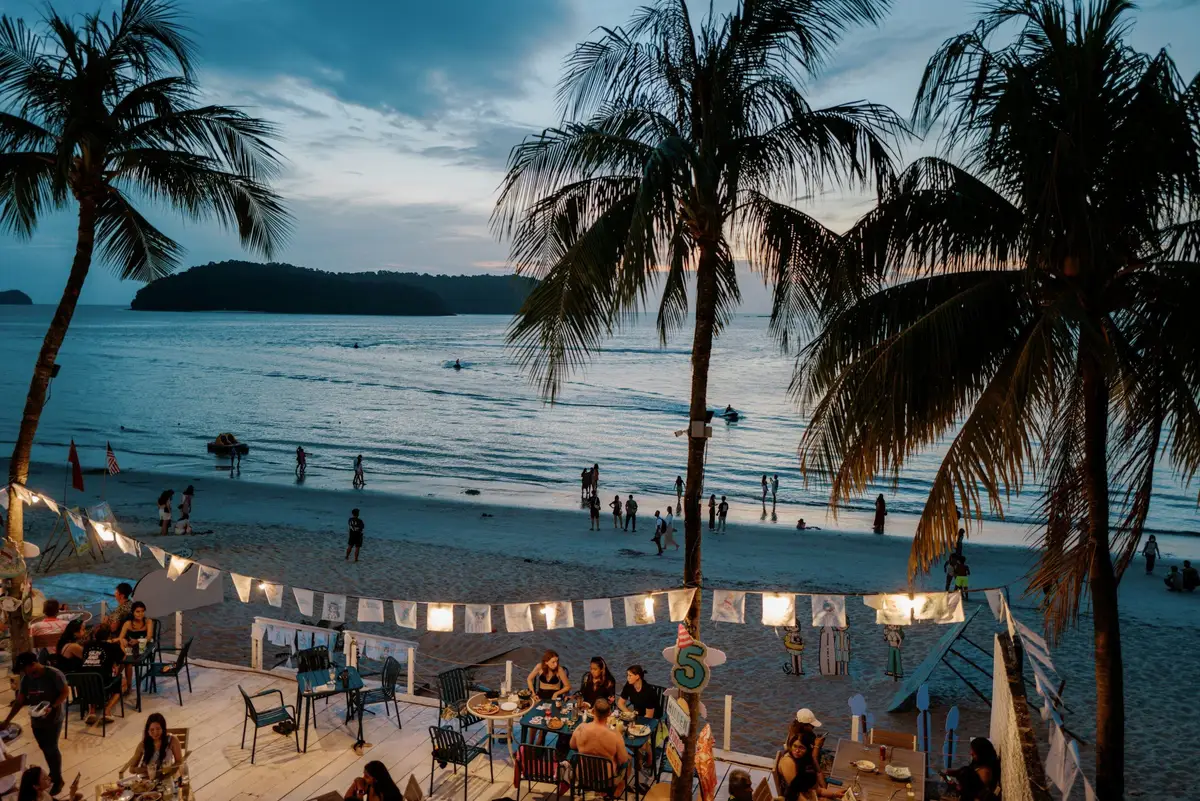 Coucher de soleil paisible sur une plage tropicale bordée de palmiers à Langkawi.