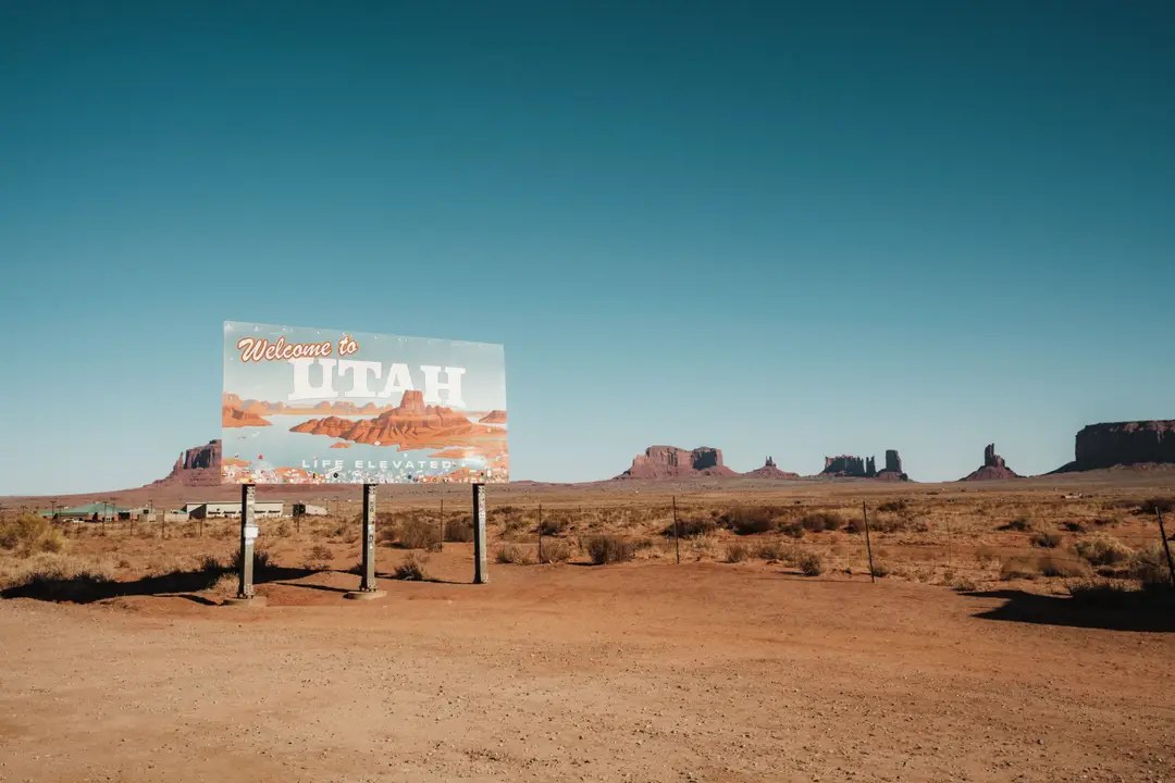Découvrez la Monument Valley avec l'emblématique panneau de bienvenue de l'Utah sous un ciel clair