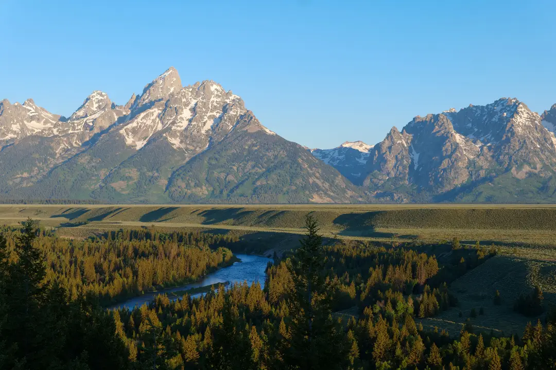 Les montagnes de Grand Teton se reflètent dans un paysage verdoyant du Wyoming.