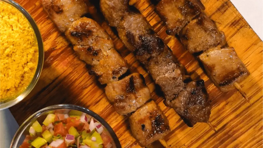Brochettes de viande grillée servies avec de la farofa