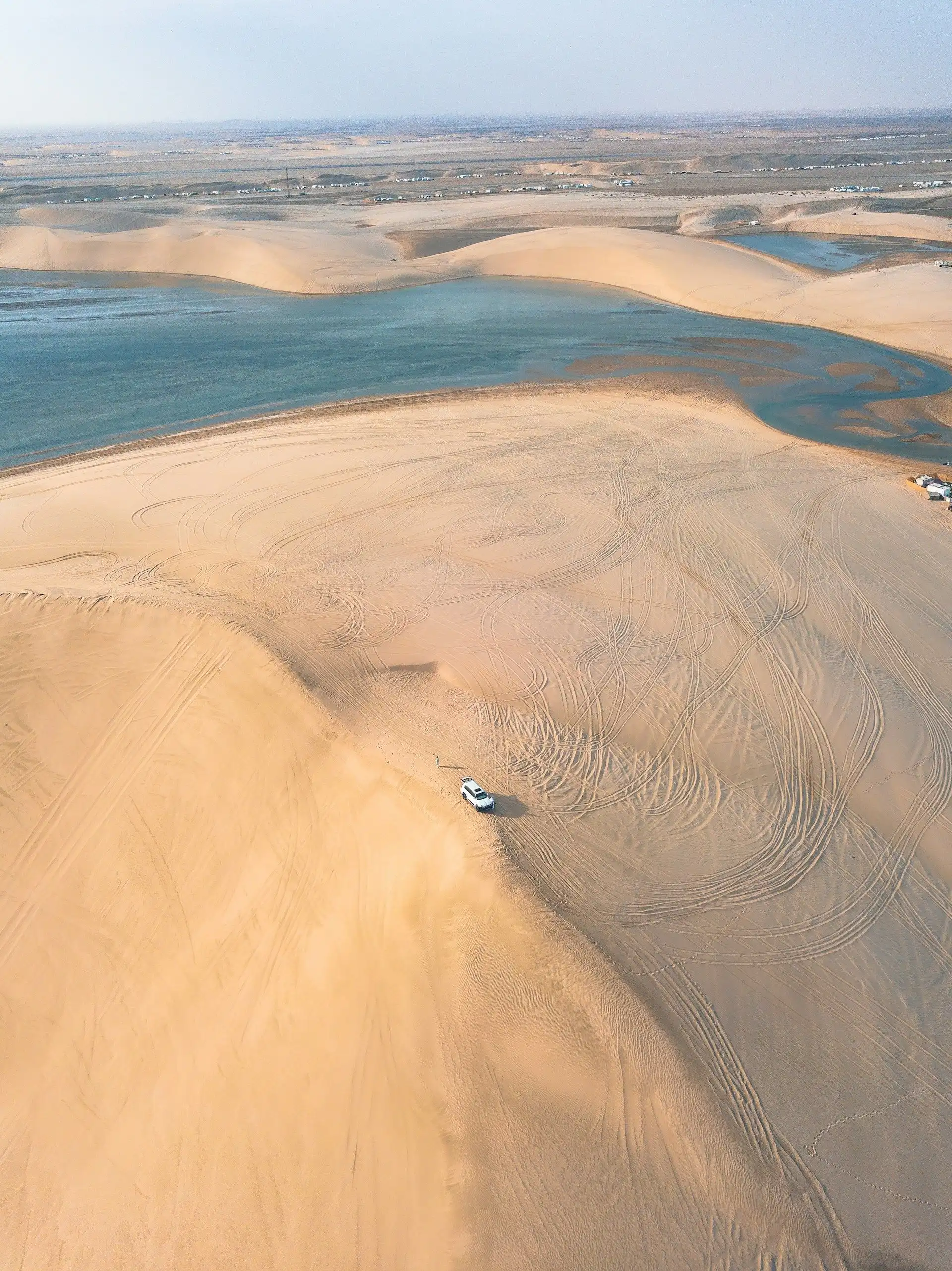 Vue aérienne des dunes de sable doré du désert se jetant directement dans les eaux bleues de la mer intérieure à Khor Al Adaid au Qatar.