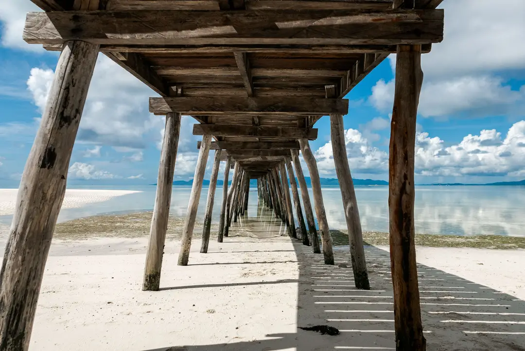 Explorez une superbe jetée en bois s'étendant sur des eaux cristallines sur une plage d'île tropicale sereine.jpg