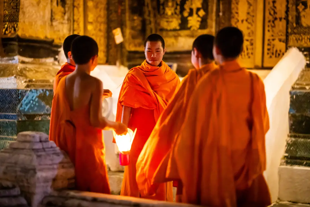 Jeunes moines bouddhistes en robe orange tenant une lanterne éclairée lors de la fête des lumières à Luang Prabang.