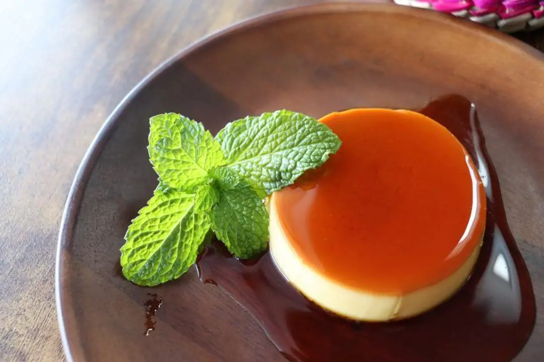 Un flan au caramel Kem Caramen, dessert très populaire au Vietnam, nappé de son coulis et décoré d'une feuille de menthe fraîche.