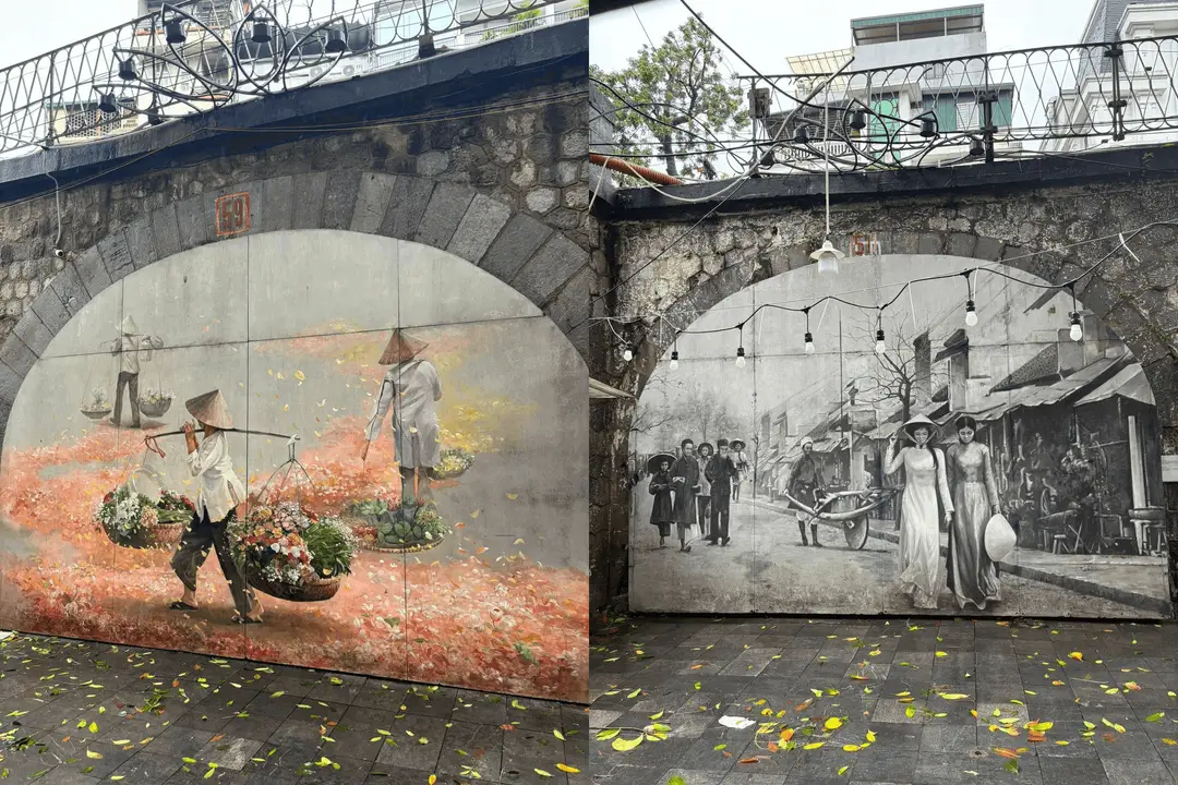 Deux grandes fresques artistiques peintes sous les arches en pierre de la rue Phung Hung à Hanoi, l'une colorée montrant des vendeuses de fleurs ambulantes et l'autre en noir et blanc illustrant une scène de rue historique.