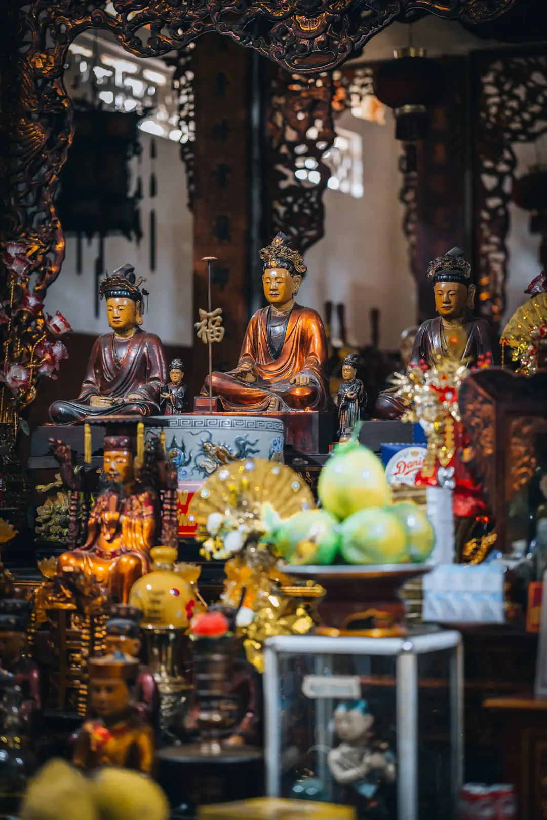 Intérieur de la boutique Bookworm Hanoi, mettant en valeur des statues traditionnelles vietnamiennes et des boiseries sculptées typiques.