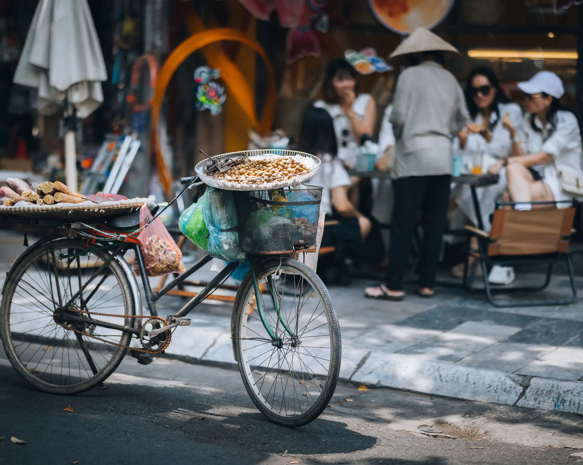 velo traditionnel de vendeur ambulant charge de marchandises dans une rue de hanoi avec des passants en arriere plan