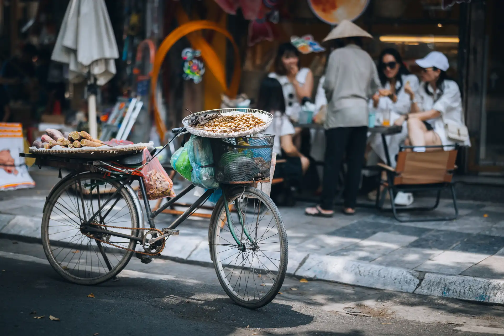 velo traditionnel de vendeur ambulant charge de marchandises dans une rue de hanoi avec des passants en arriere plan