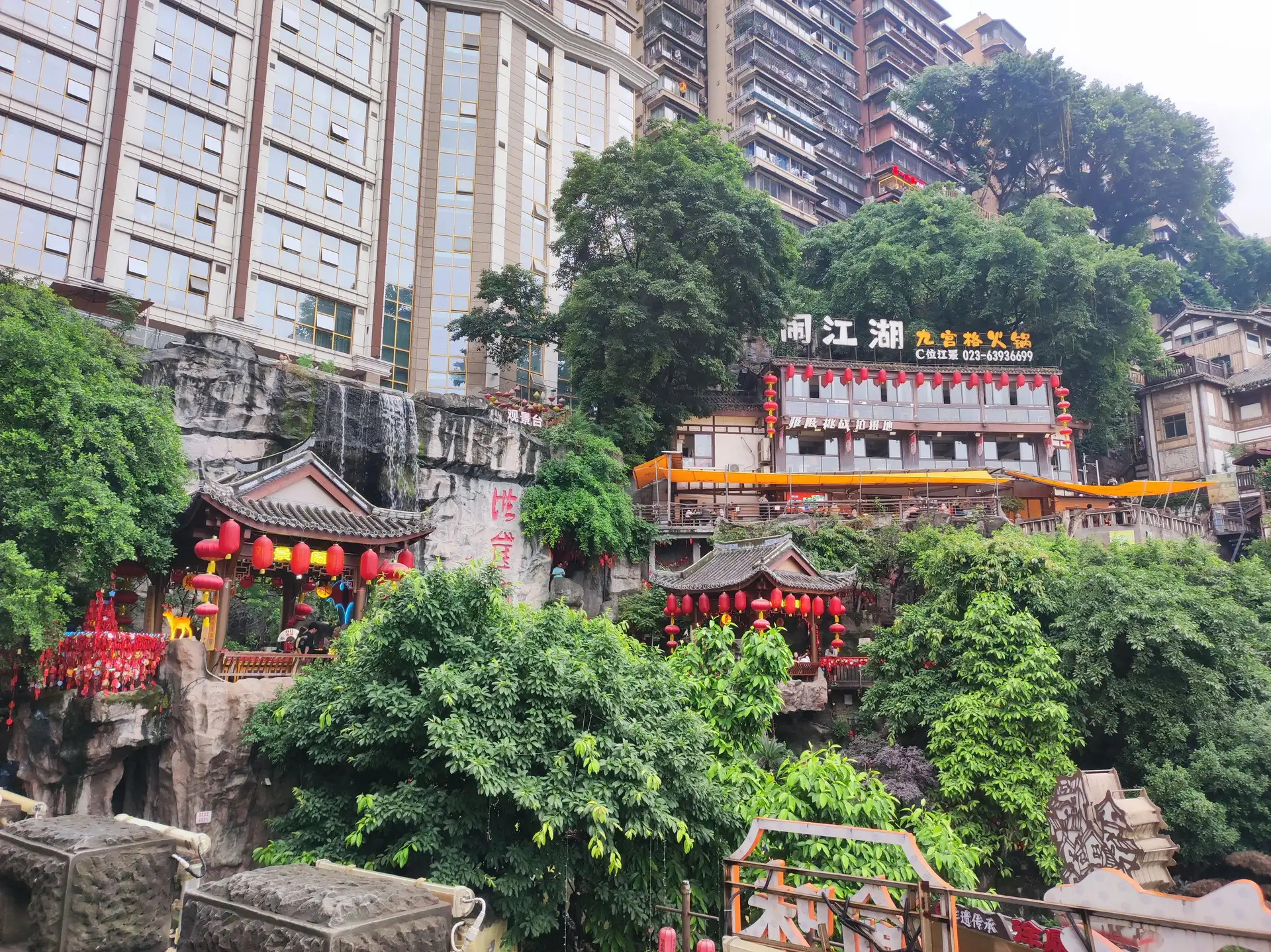 batiments traditionnels aux lanternes rouges construits sur une falaise verdoyante au pied de grands immeubles modernes a chongqing