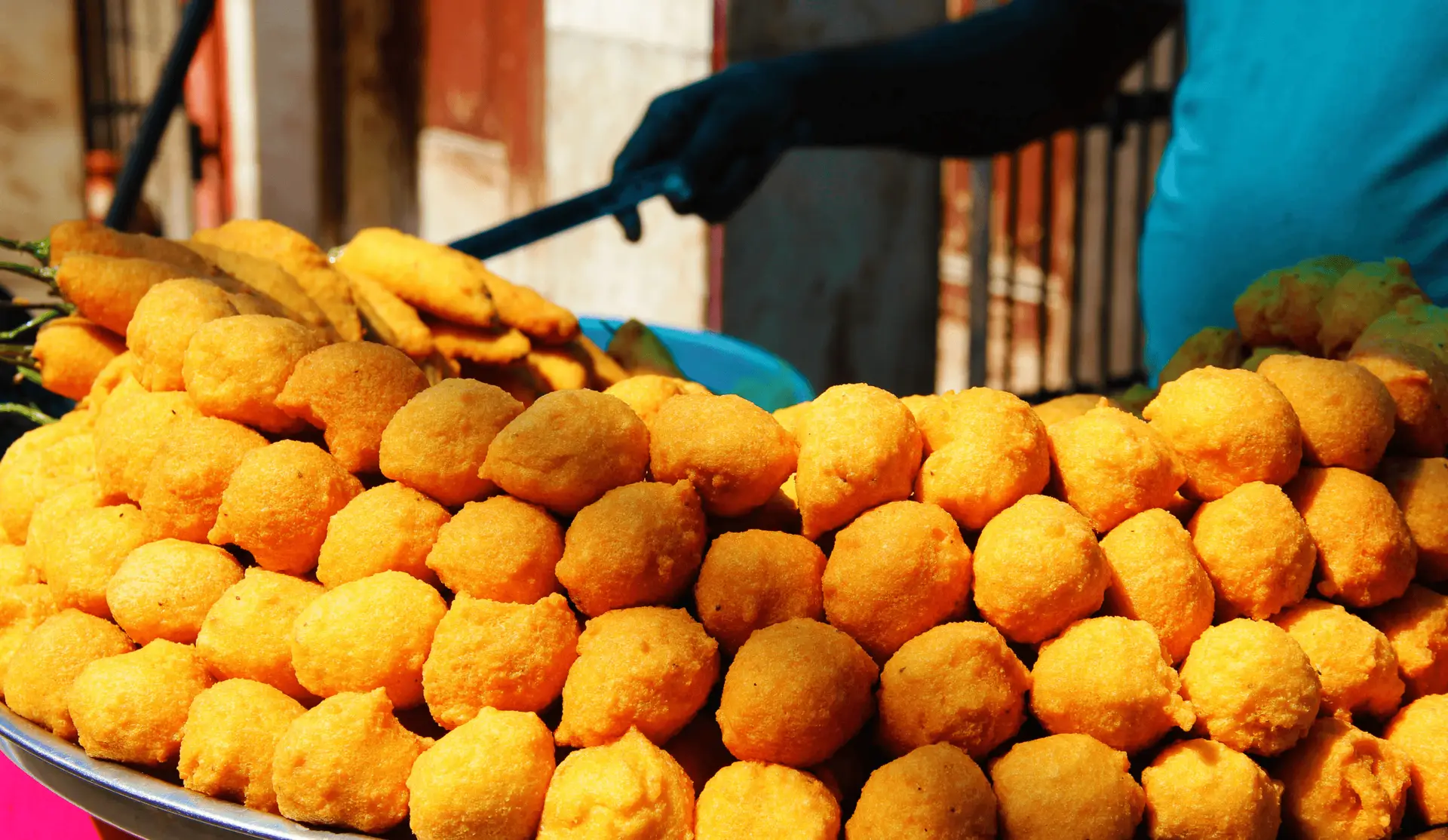Gros plan sur une pyramide de Ram Ladoo, des boulettes de lentilles frites dorées, servies sur un étal de rue traditionnel à Old Delhi.