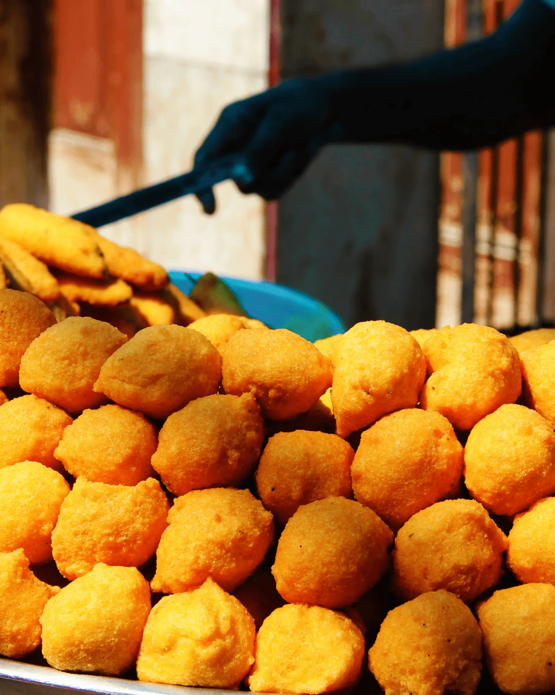 Gros plan sur une pyramide de Ram Ladoo, des boulettes de lentilles frites dorées, servies sur un étal de rue traditionnel à Old Delhi.