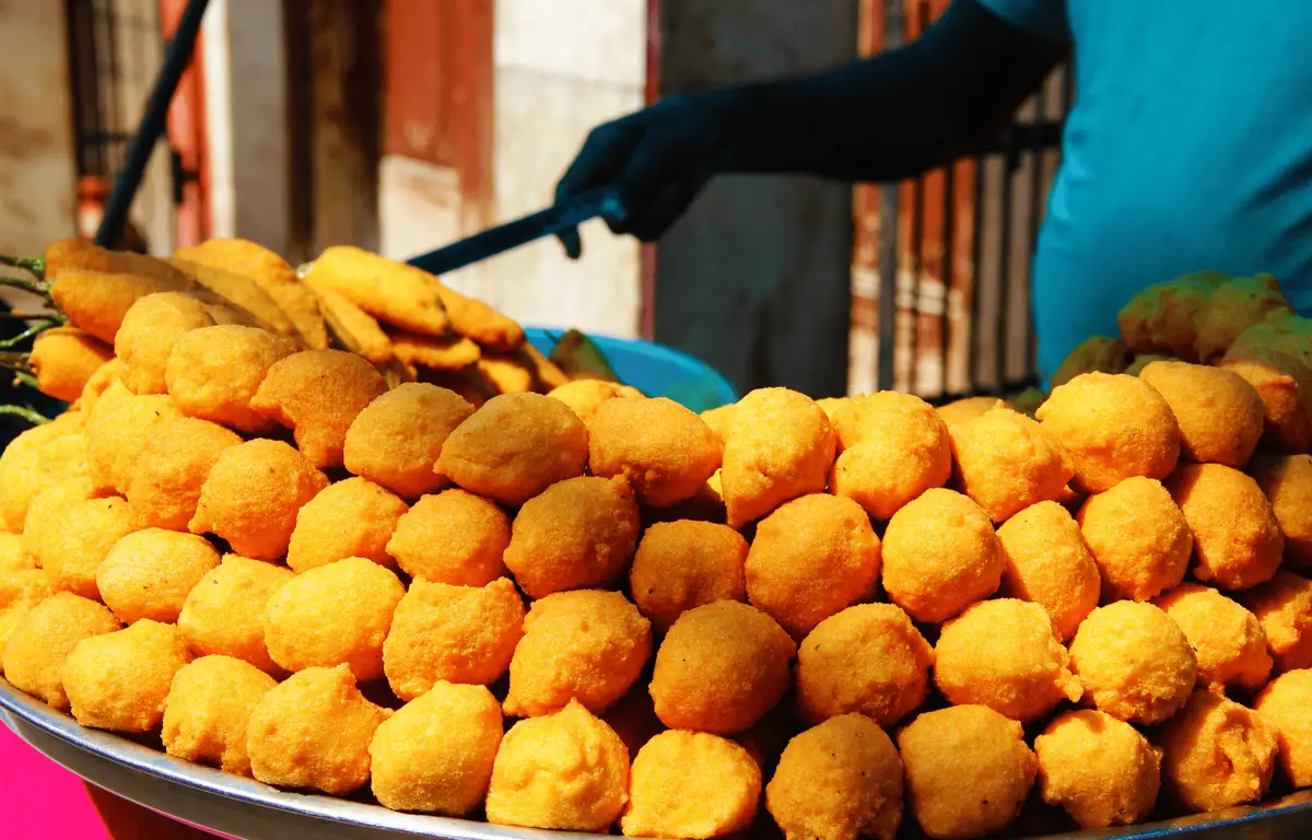 Gros plan sur une pyramide de Ram Ladoo, des boulettes de lentilles frites dorées, servies sur un étal de rue traditionnel à Old Delhi.