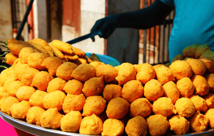 Gros plan sur une pyramide de Ram Ladoo, des boulettes de lentilles frites dorées, servies sur un étal de rue traditionnel à Old Delhi.