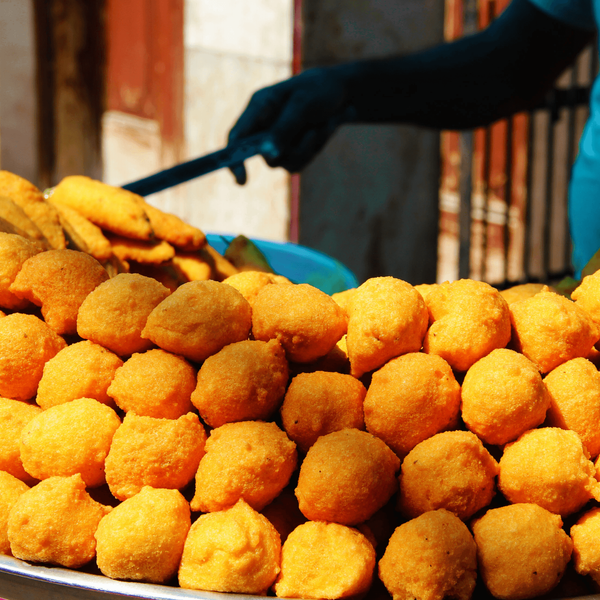 Gros plan sur une pyramide de Ram Ladoo, des boulettes de lentilles frites dorées, servies sur un étal de rue traditionnel à Old Delhi.