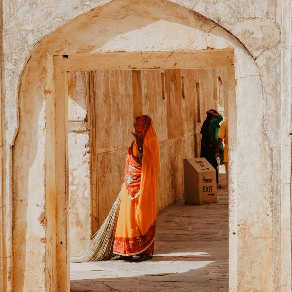 Porte avec une femme indienne portant un sari orange et un balai à la main