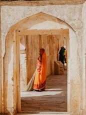 Porte avec une femme indienne portant un sari orange et un balai à la main