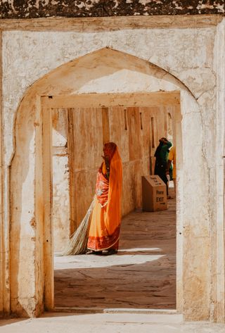 Porte avec une femme indienne portant un sari orange et un balai à la main