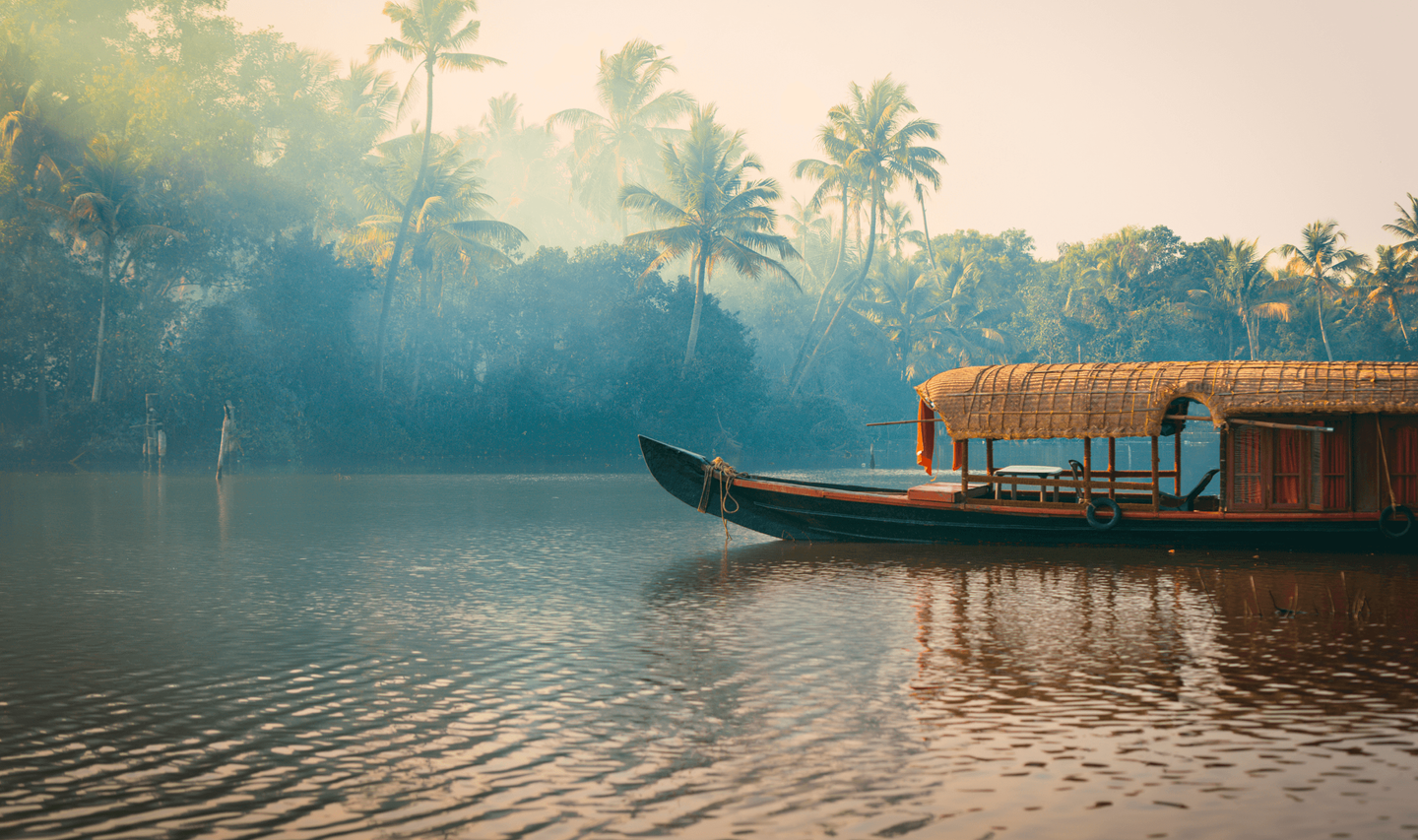 Travel in Asia - A boat floating on a river surrounded by jungle in the backwaters of Kerala, India