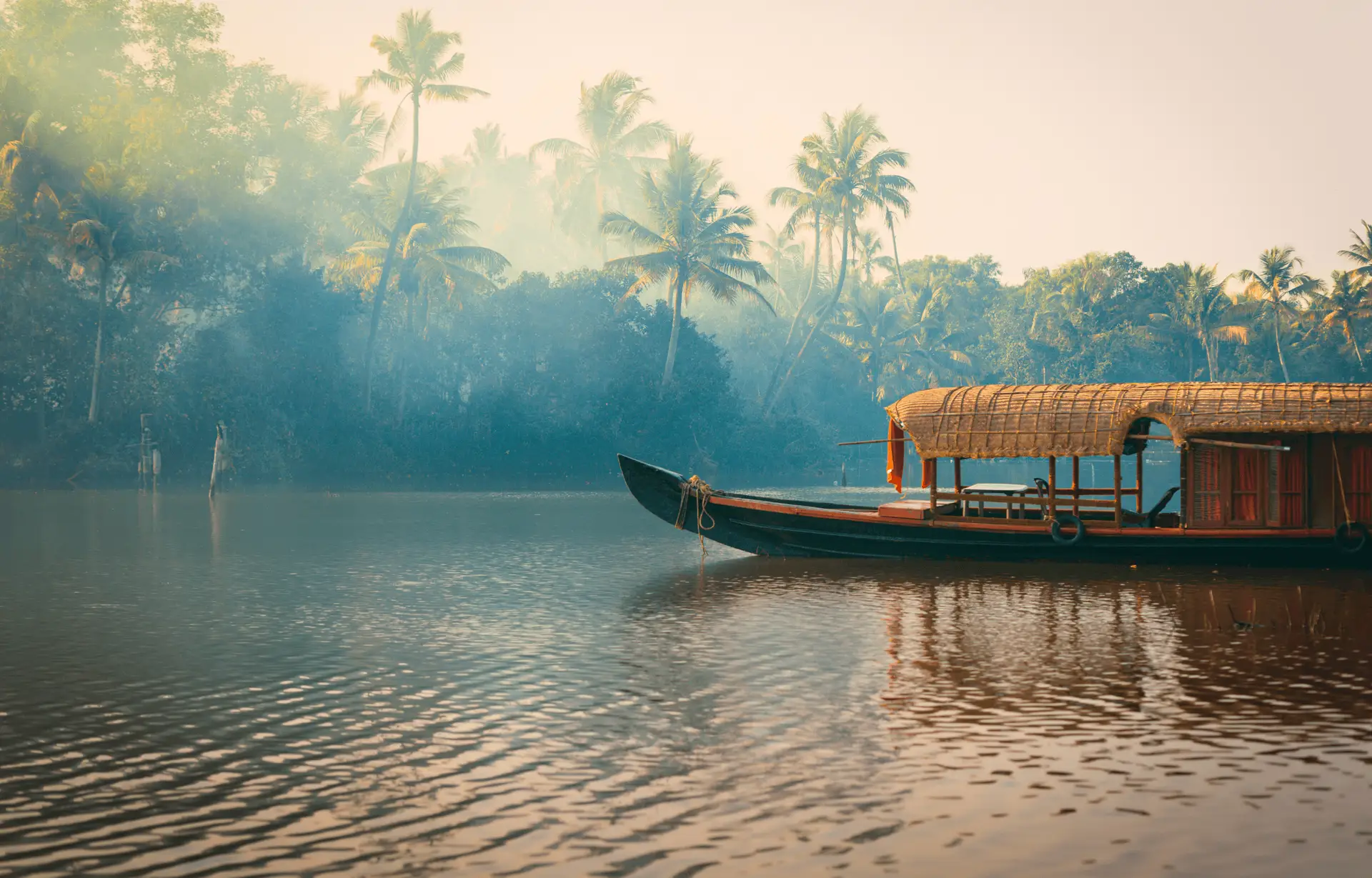 Travel in Asia - A boat floating on a river surrounded by jungle in the backwaters of Kerala, India