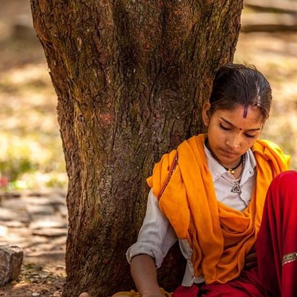 Indisches Mädchen lehnt sich an Baum nachdenklich