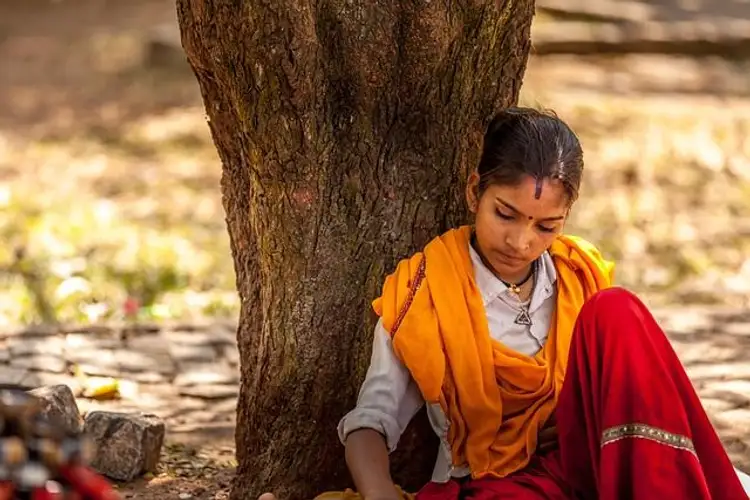Indisches Mädchen lehnt sich an Baum nachdenklich