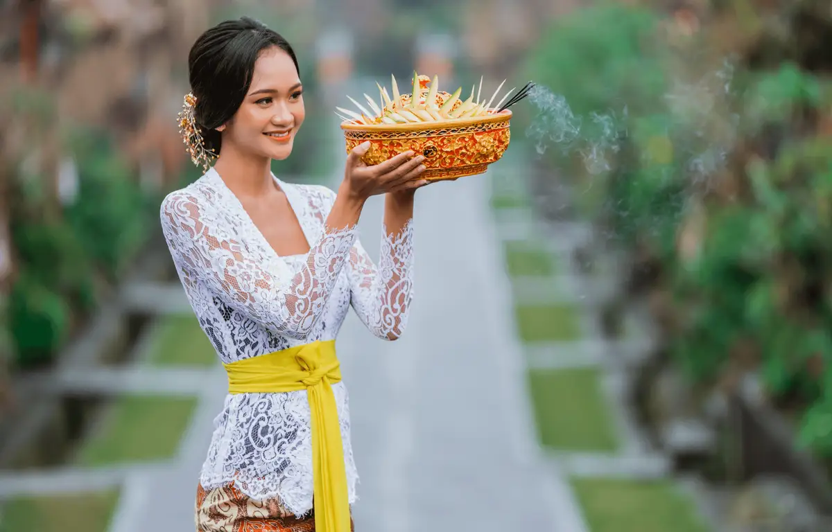 Voyage en Asie — Femme balinaise en kebaya tenant une offrande Canang Sari lors d'une cérémonie traditionnelle.