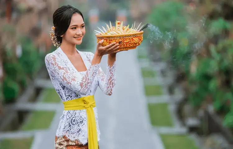 Voyage en Asie — Femme balinaise en kebaya tenant une offrande Canang Sari lors d'une cérémonie traditionnelle.