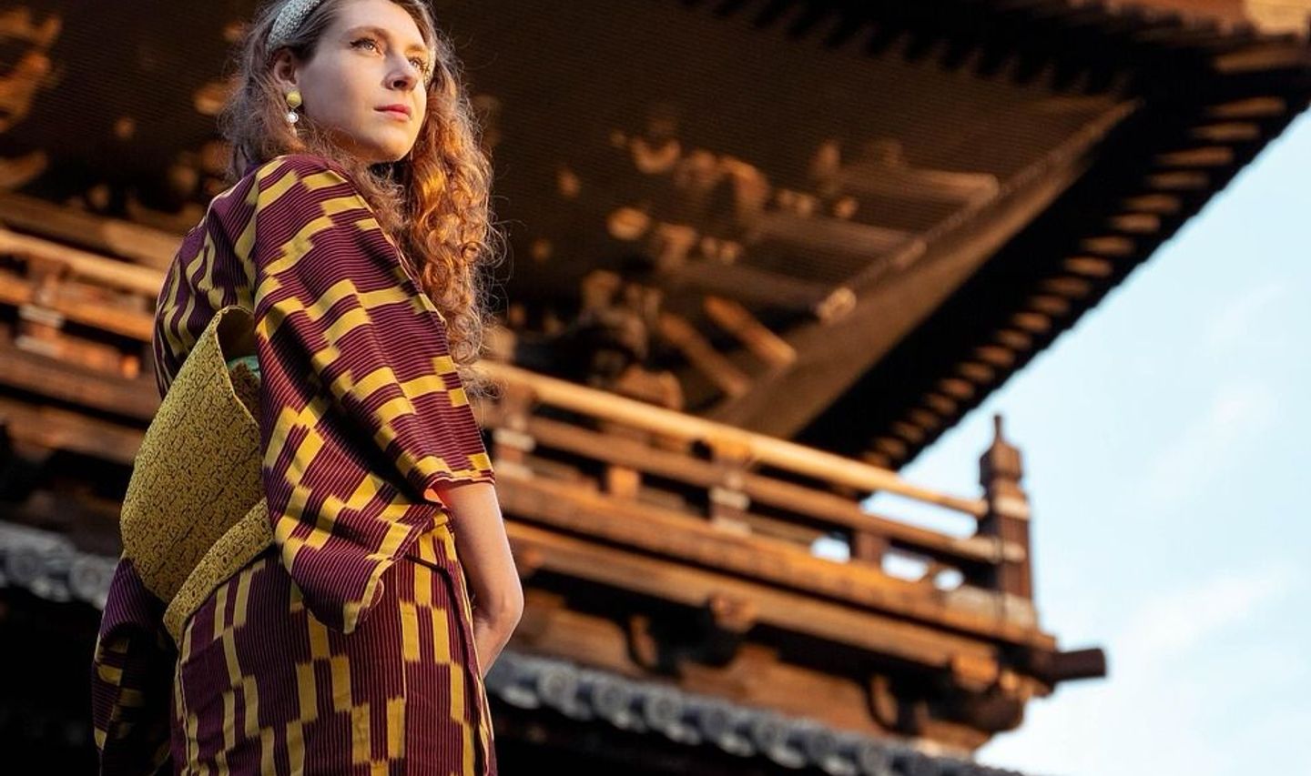 Travel in Asia - A young woman wearing a Japanese yukata standing in front of temple in Kyoto