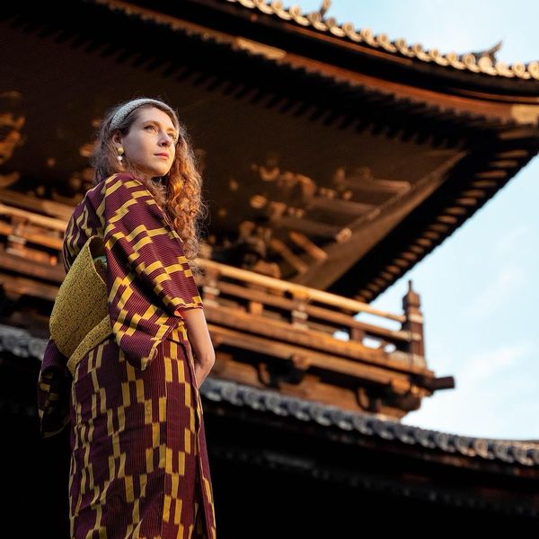 Travel in Asia - A young woman wearing a Japanese yukata standing in front of temple in Kyoto
