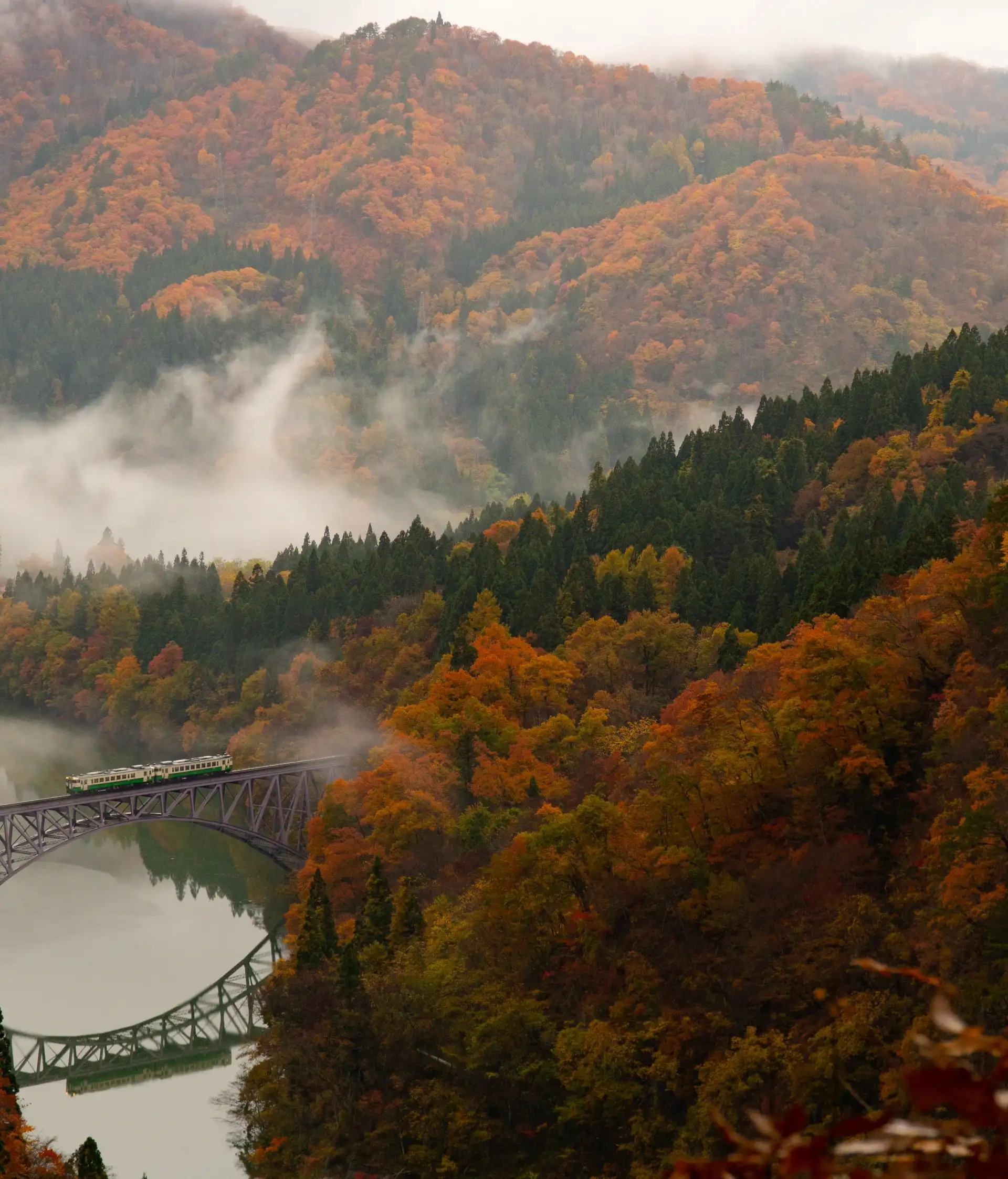 pont de chemin de fer panoramique traversant une riviere au milieu de collines forestieres en automne avec brume au japon