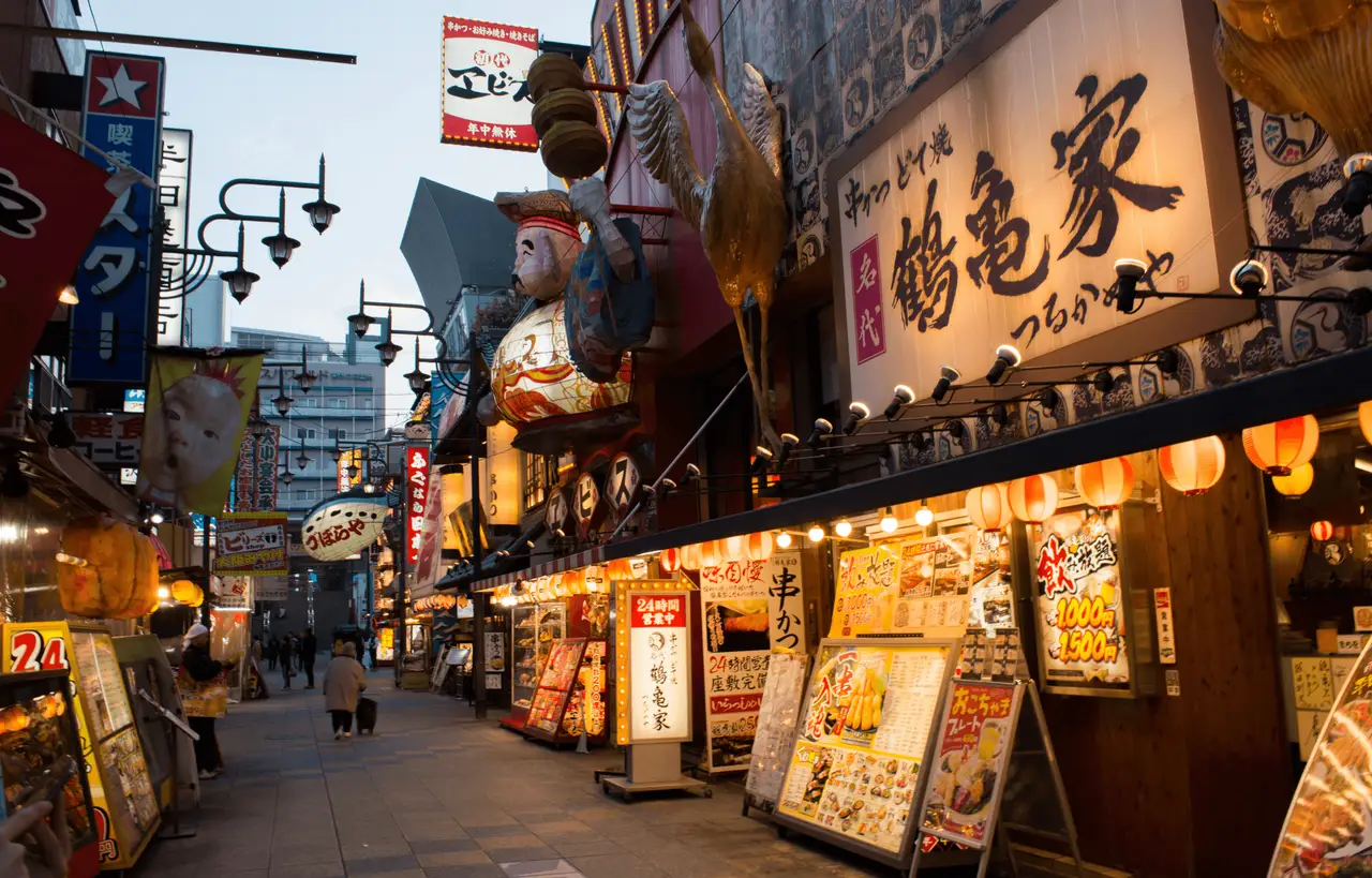 Beleuchtete Gasse mit traditionellen Restaurant-Schildern im Shinsekai-Viertel in Osaka bei Nacht